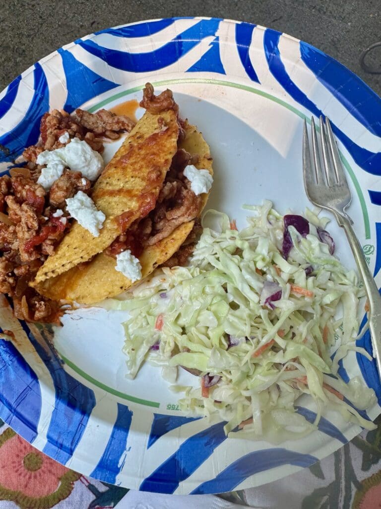 Tacos with coleslaw on a paper plate.