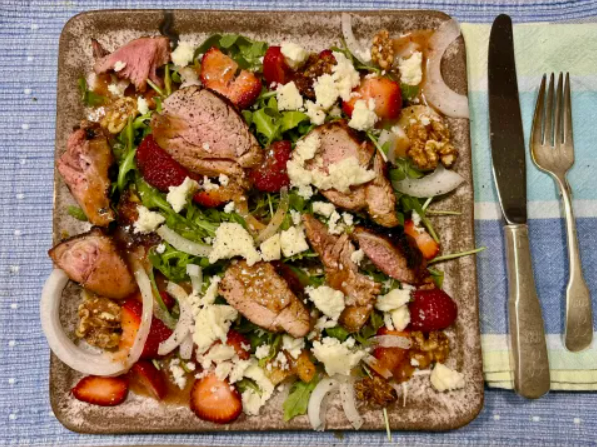 A plate of food with meat, cheese and strawberries.