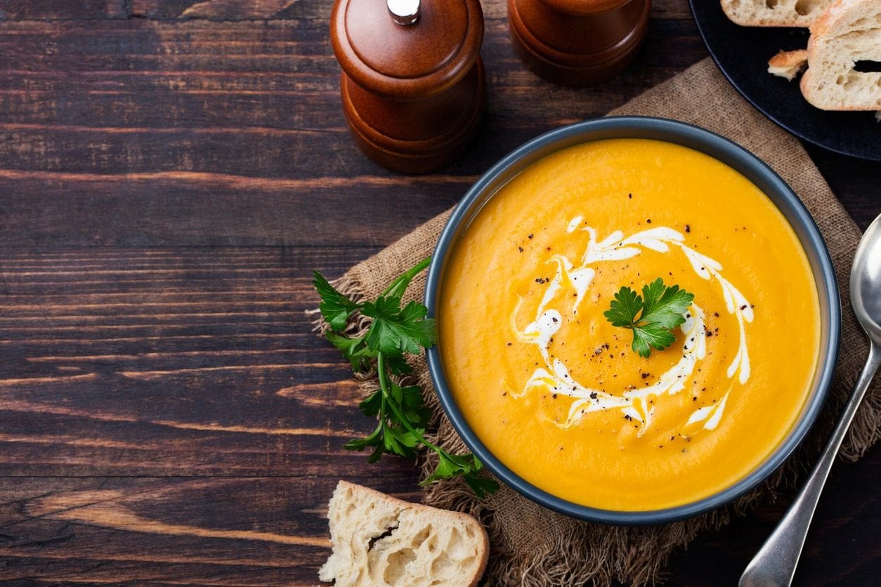 A bowl of soup on top of a wooden table.