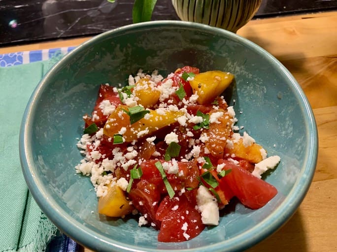 A bowl of food with tomatoes and feta cheese.