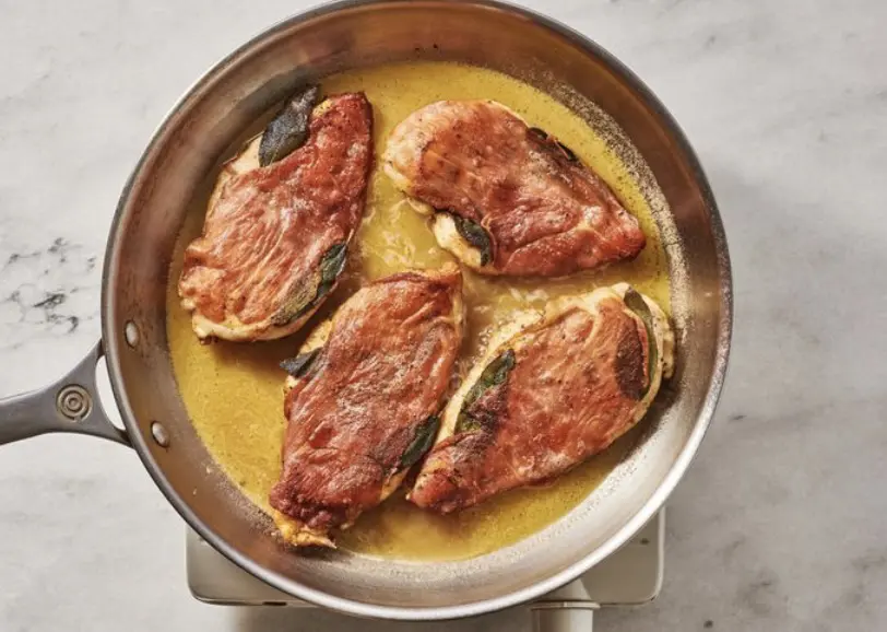 A pan with some meat in it on top of a stove.