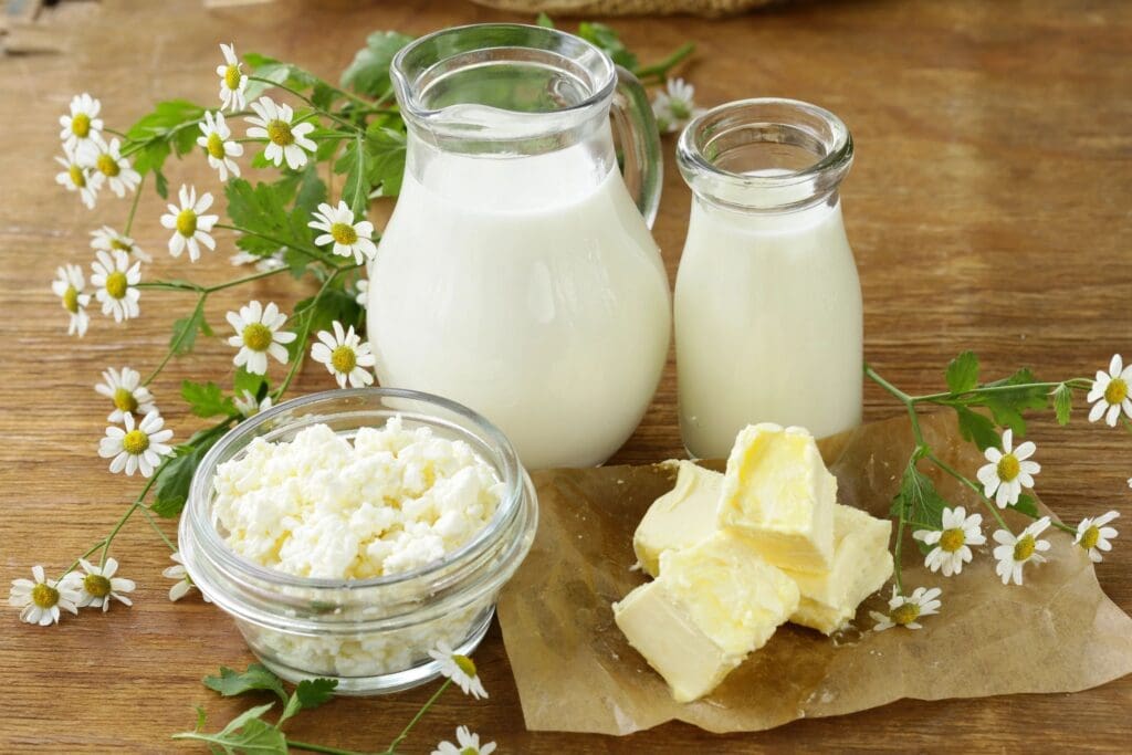 A table topped with milk and butter next to flowers.