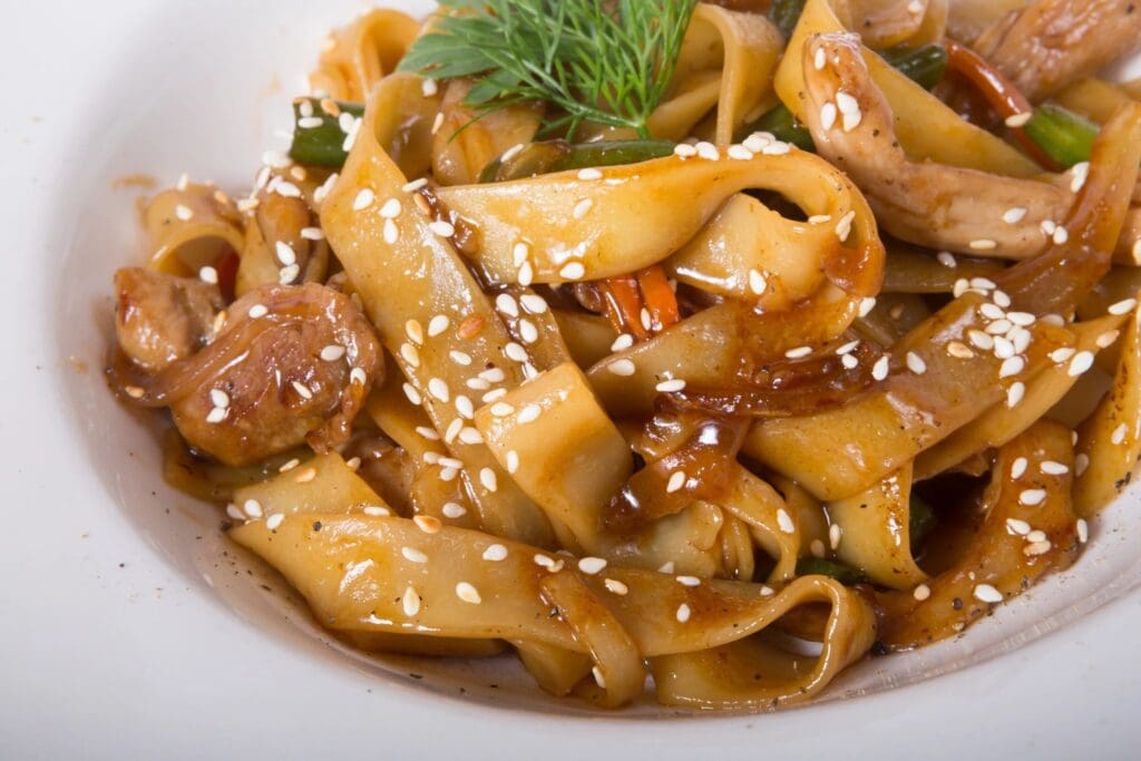 A close up of noodles with meat and sesame seeds