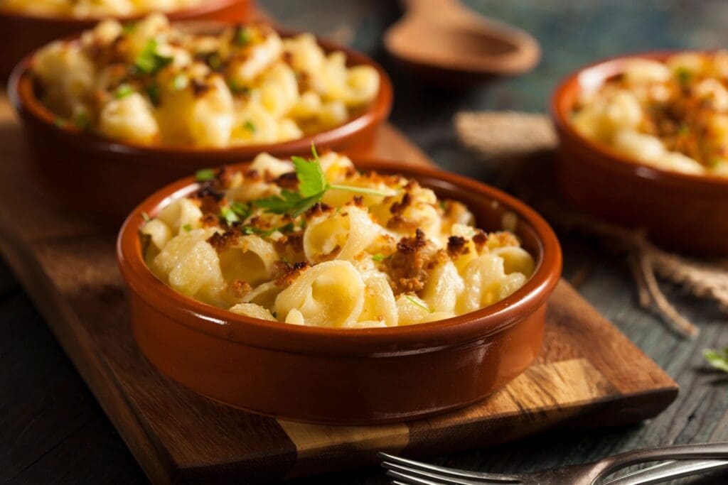 Two bowls of macaroni and cheese on a wooden board.