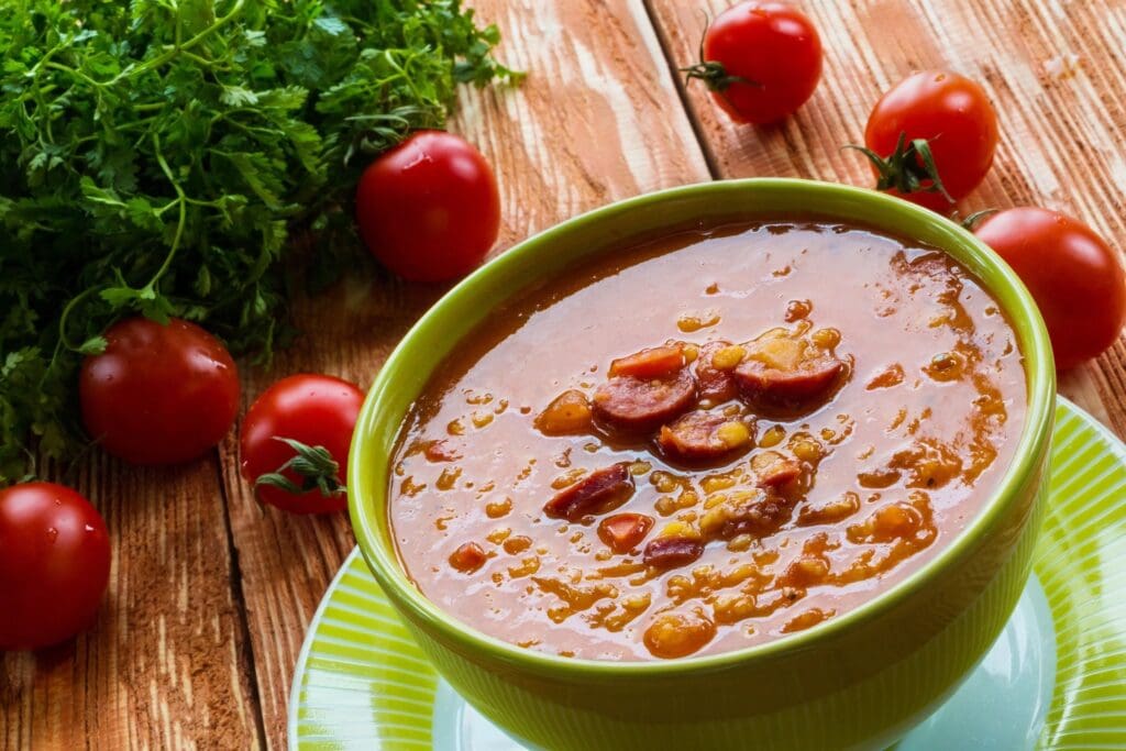 A bowl of soup with tomatoes and parsley.