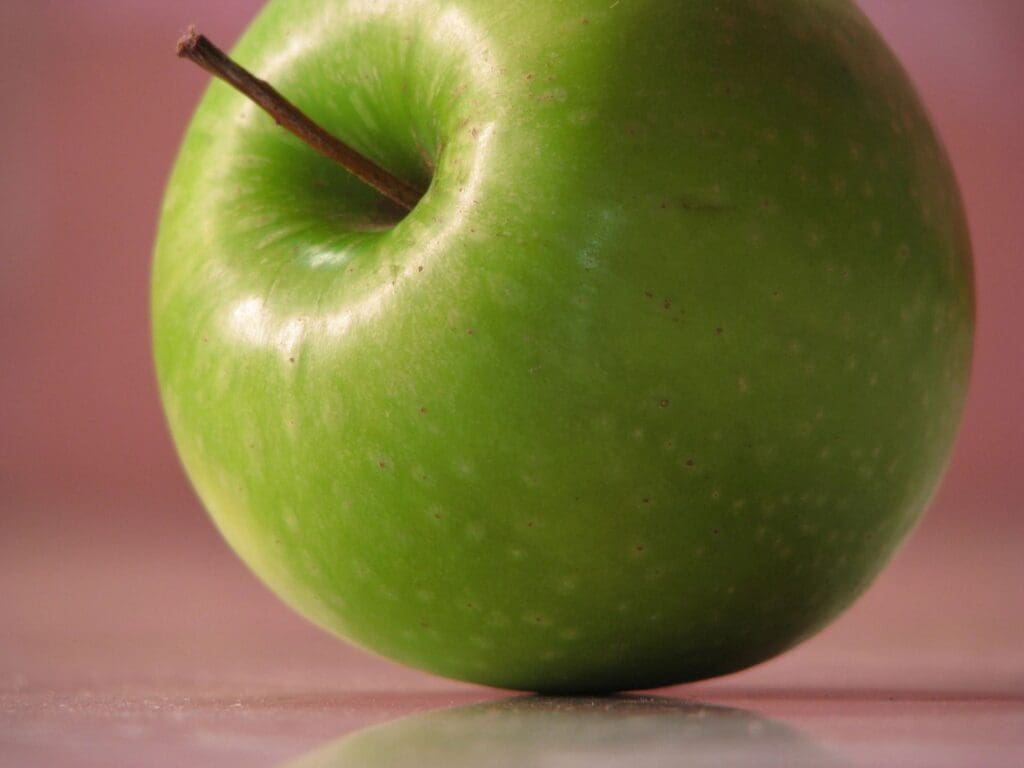 A green apple sitting on top of a table.