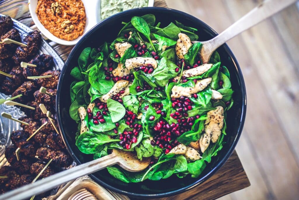 A bowl of salad with two forks in it.