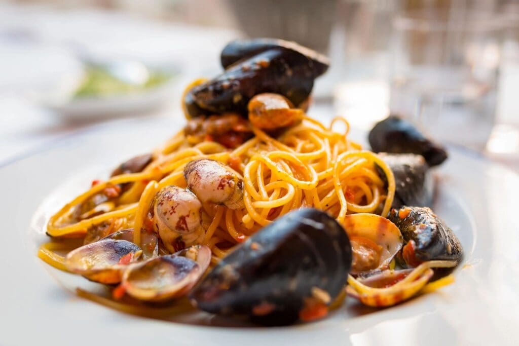 A plate of pasta with mussels and sauce.