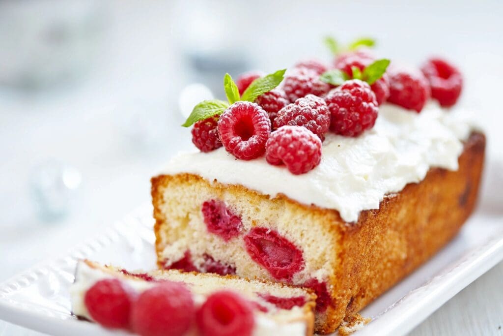 A piece of cake with raspberries on top.