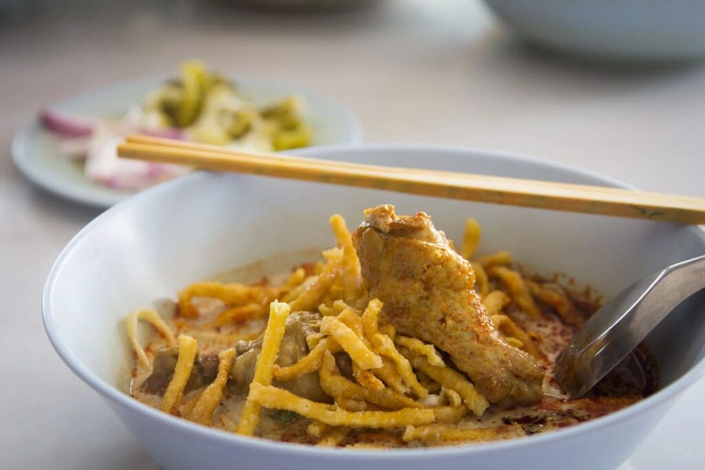 A bowl of food with noodles and meat.