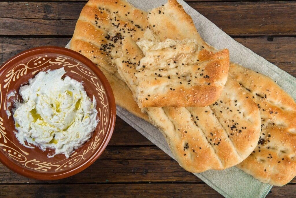 A bowl of yogurt and some bread on the table