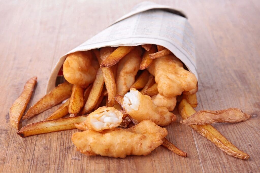 A paper bag filled with fish and chips.