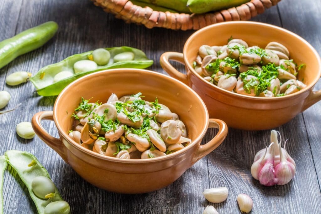 Two bowls of food on a table with green vegetables.