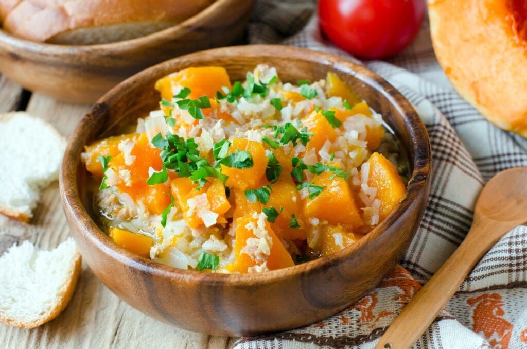 A bowl of rice and squash on the table.