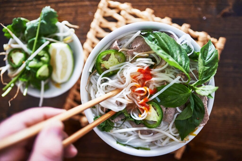 A bowl of soup with chopsticks in it.