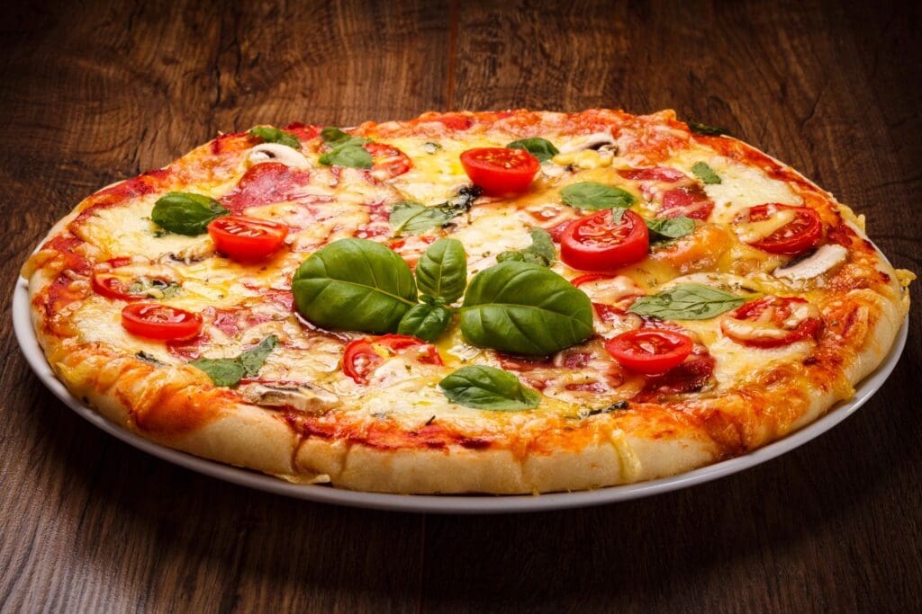 A pizza with tomatoes and basil on it.