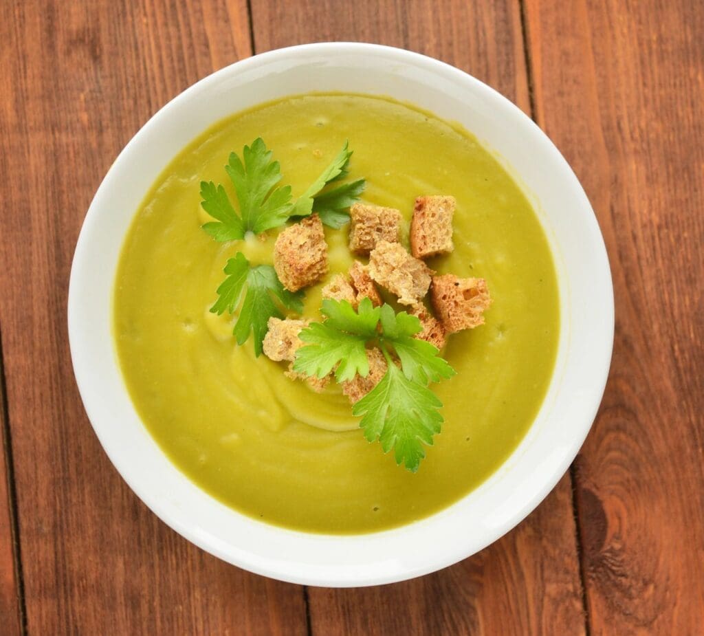 A bowl of soup with croutons and parsley.