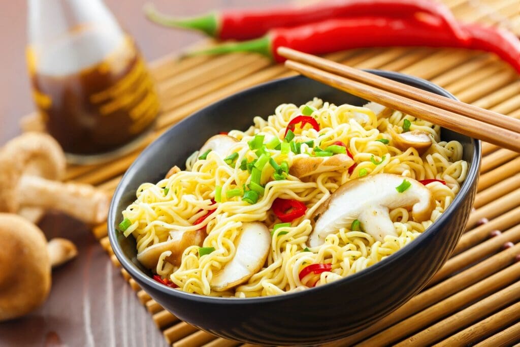 A bowl of noodles with mushrooms and peppers.