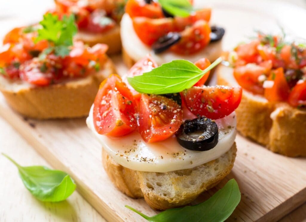 A wooden board topped with slices of bread covered in cheese and tomatoes.