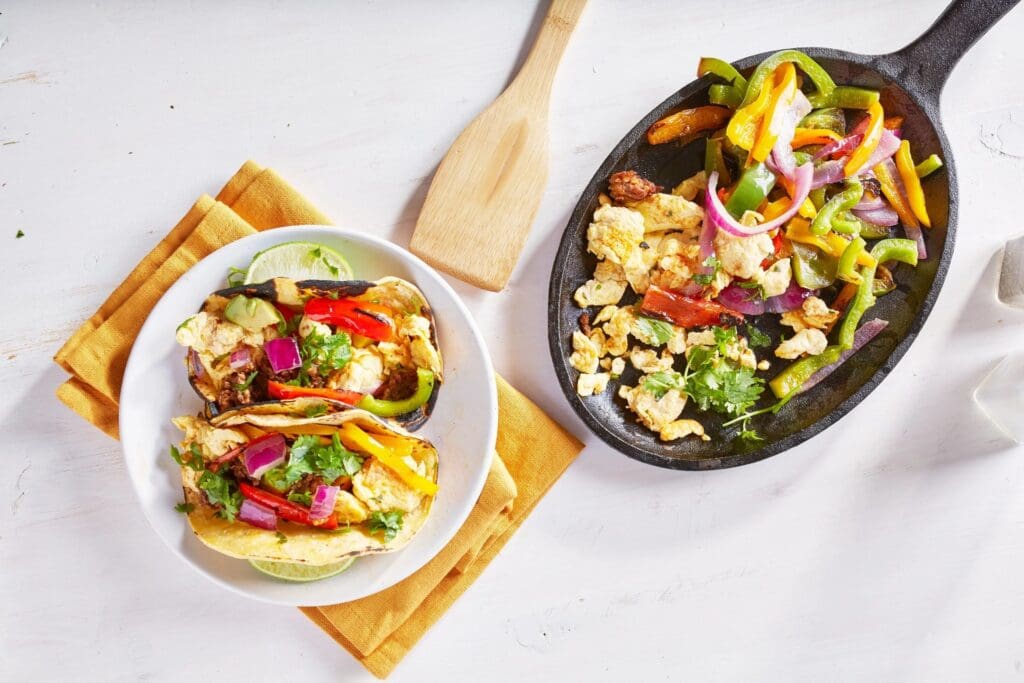 Two bowls of food on a table with a wooden spoon.