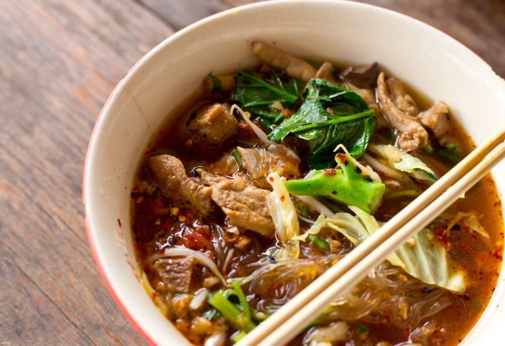 A bowl of food with meat and vegetables.