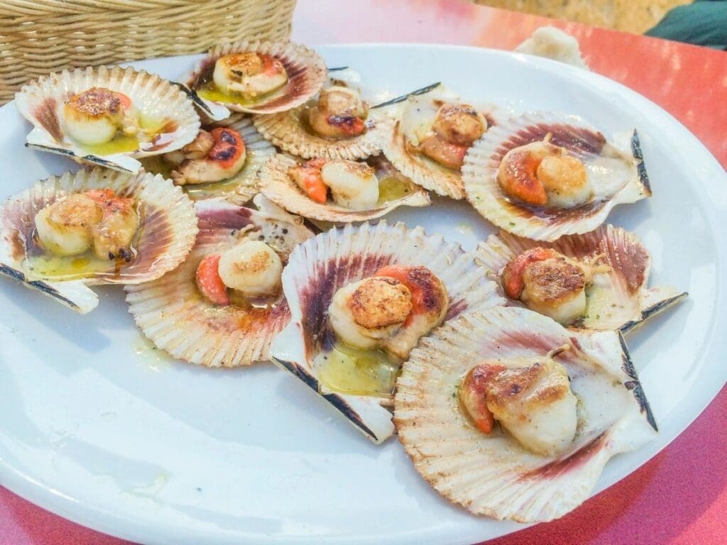 A plate of scallops with bacon on top.