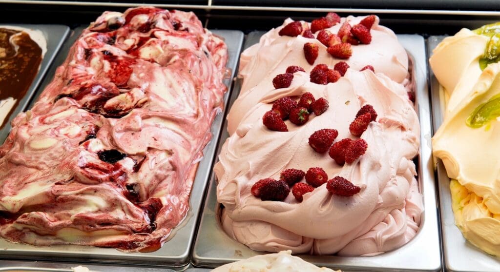 Two pans of strawberry ice cream on a table.