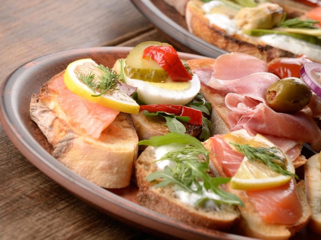 A plate of food with bread, ham and vegetables.