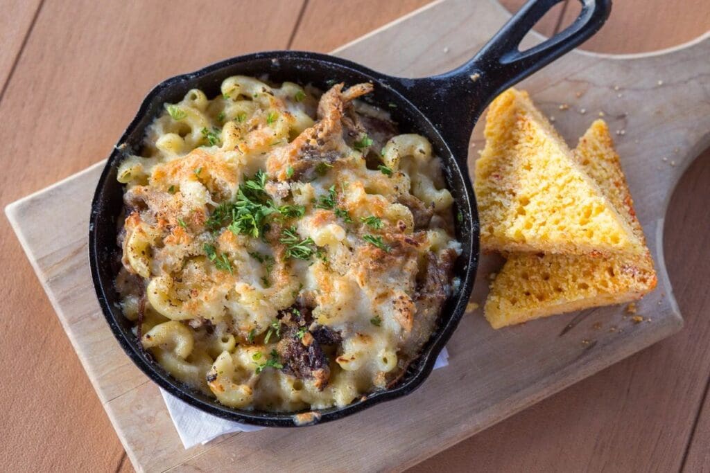 A pan of macaroni and cheese with some bread on the side.