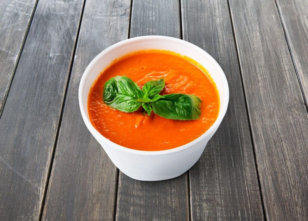 A bowl of soup with basil leaves on top.