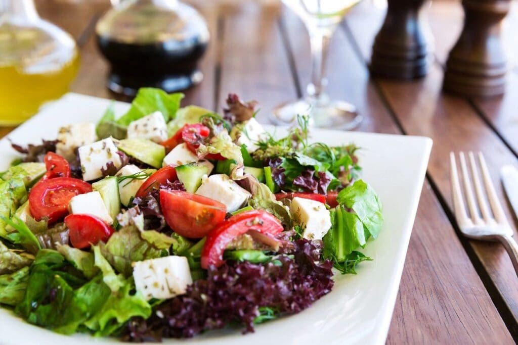 A salad with feta cheese and tomatoes on top of it.