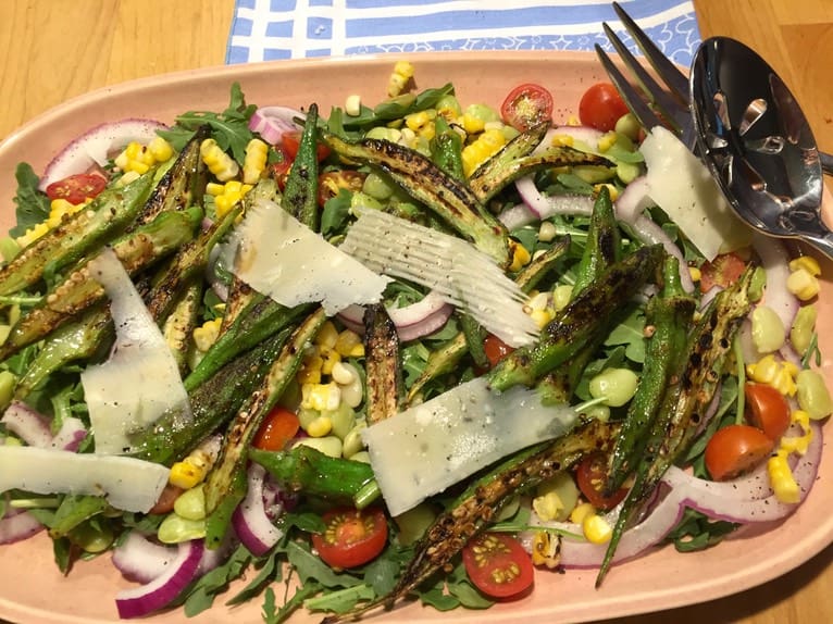 A plate of salad with asparagus, corn and tomatoes.