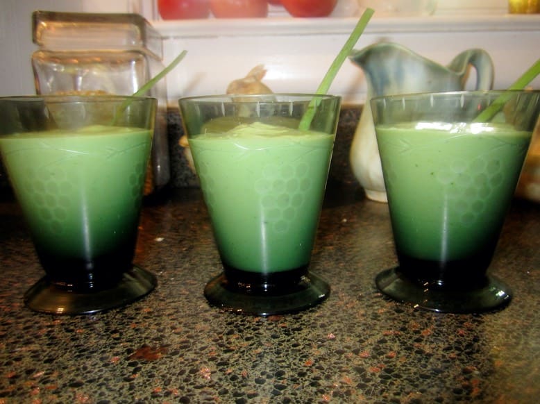 Three glasses of green smoothie on a table.