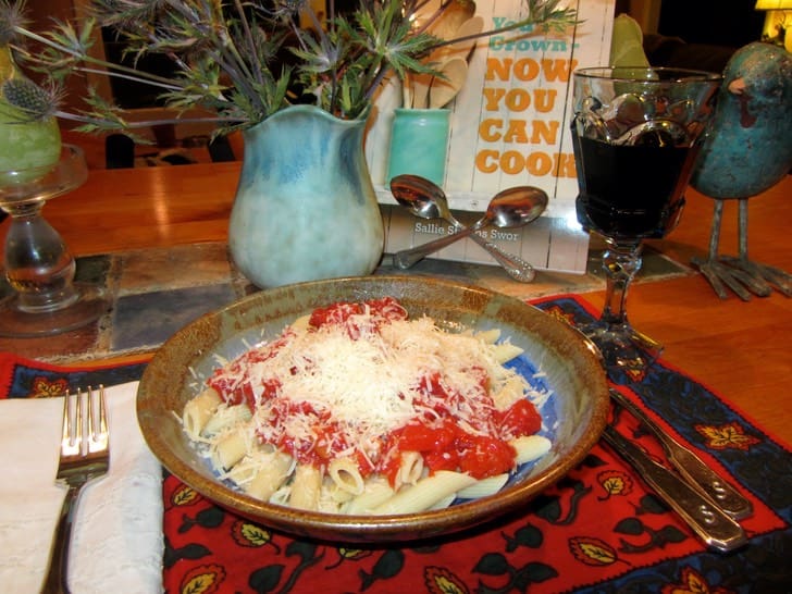 A bowl of pasta with sauce and cheese on the table.