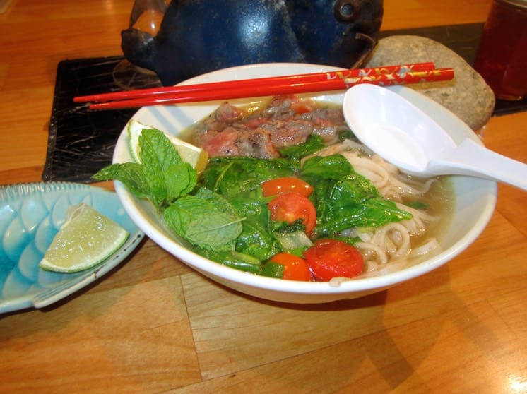 A bowl of noodles with meat and vegetables.