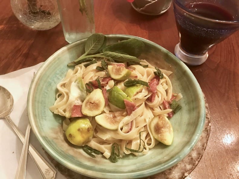 A bowl of pasta with vegetables on the side.