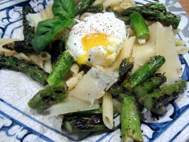 A plate of pasta with asparagus and an egg.