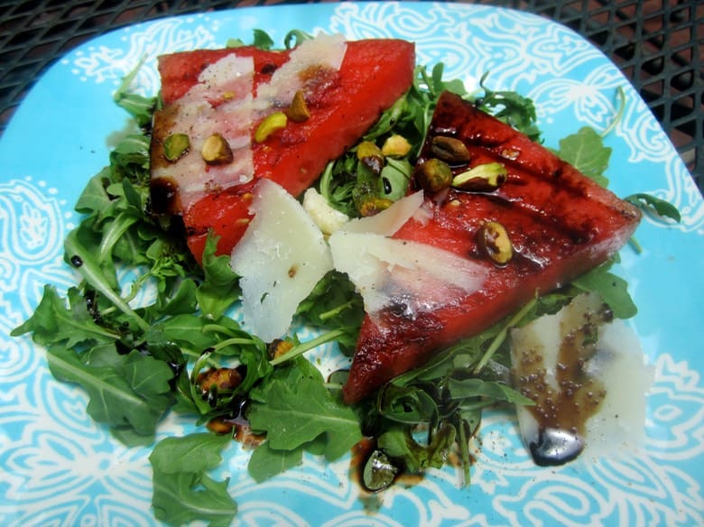 A plate of food with watermelon and greens.