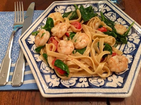 A plate of pasta with shrimp and tomatoes.