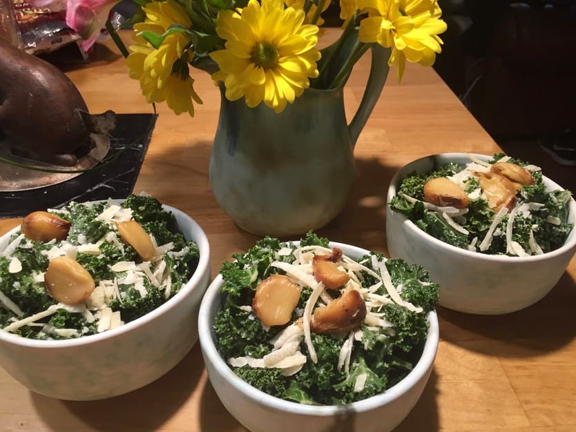 Three bowls of food on a table with flowers.