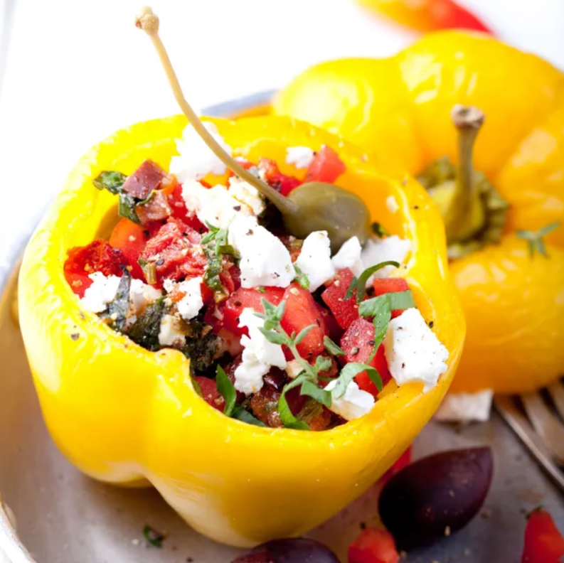 A yellow bell pepper with feta cheese and olives.