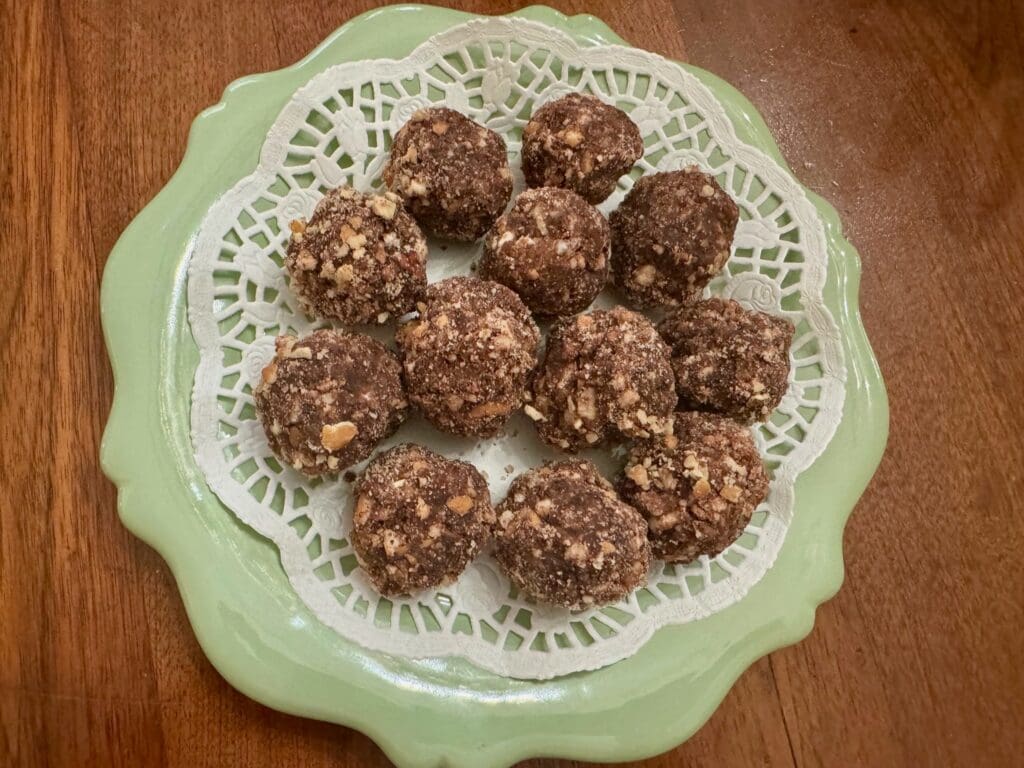 A plate of nuts and chocolate balls on top of a table.