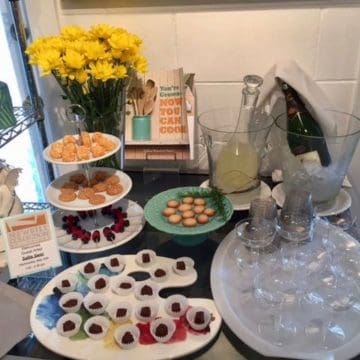 A table with snacks, drinks, and flowers.