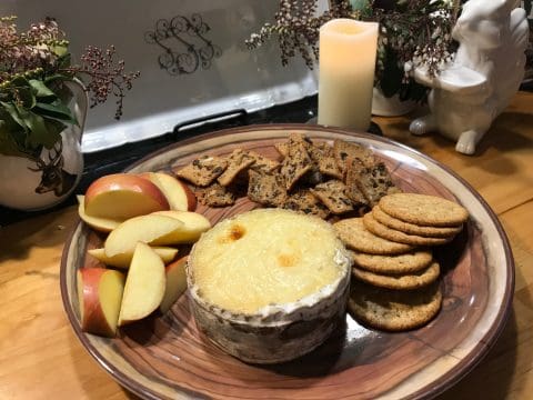 Cheese, crackers, apples on a wooden plate.