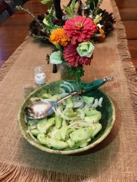 A bowl of cucumber salad on a table.