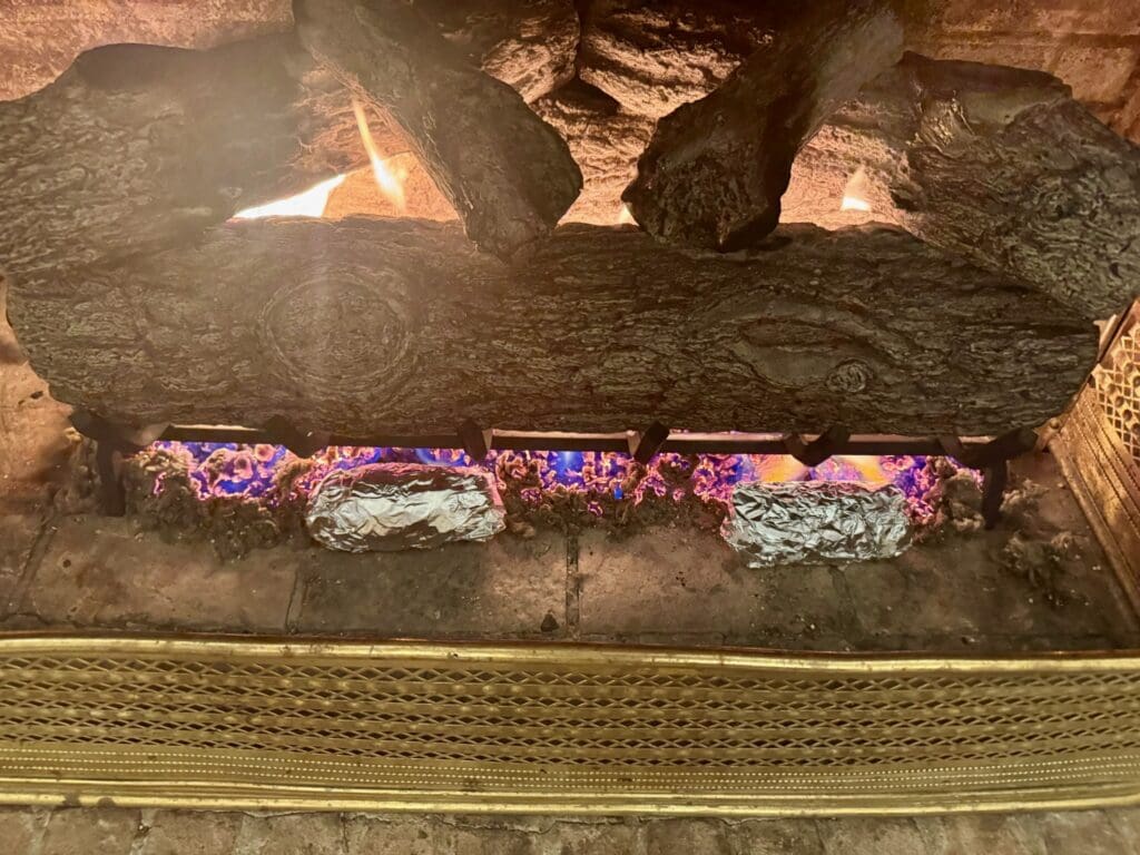 Fireplace with logs and foil-wrapped items.