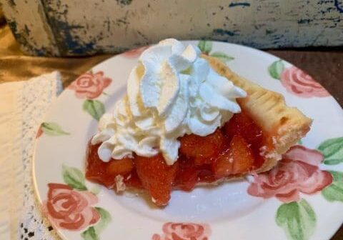 Strawberry pie with whipped cream on a plate.