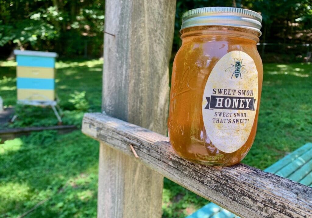 Jar of honey with bee label on wood.