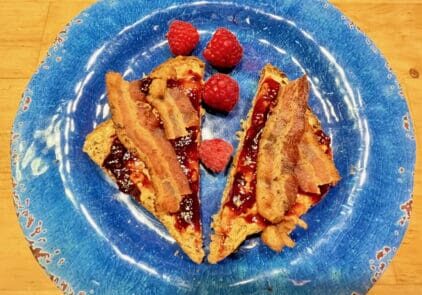 Bacon and raspberry french toast on a blue plate.