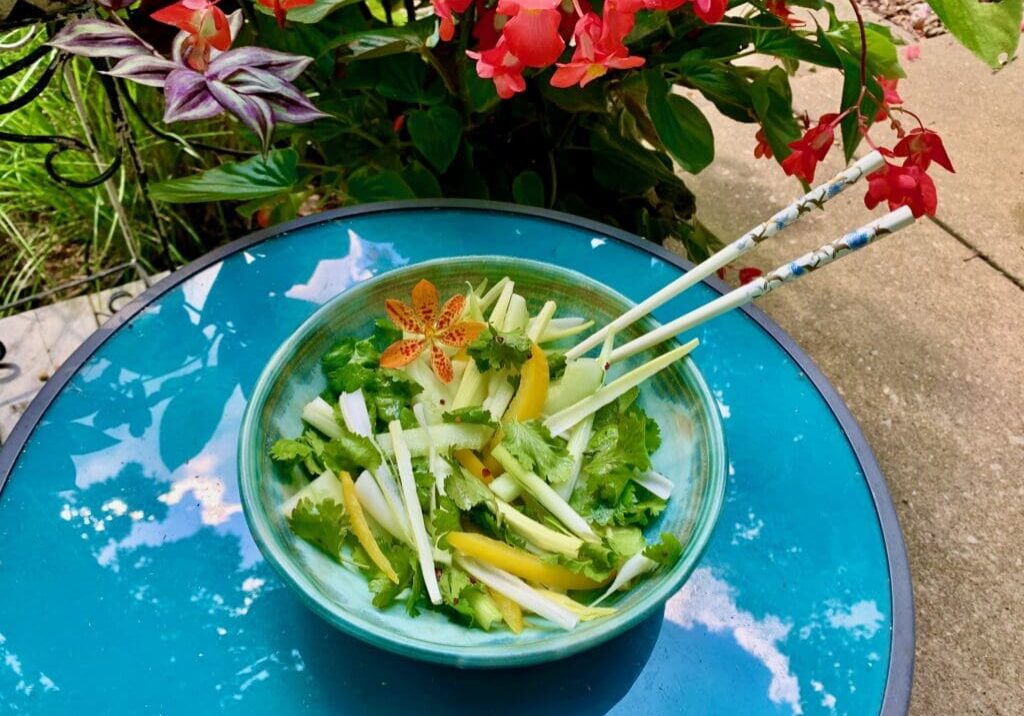 Green salad with chopsticks on a table.